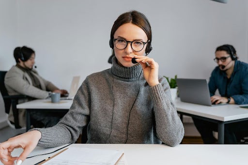 woman speaking on headset sitting at desk