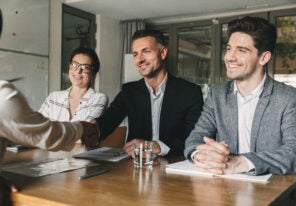 Three business partners in office handshaking with woman, as suc