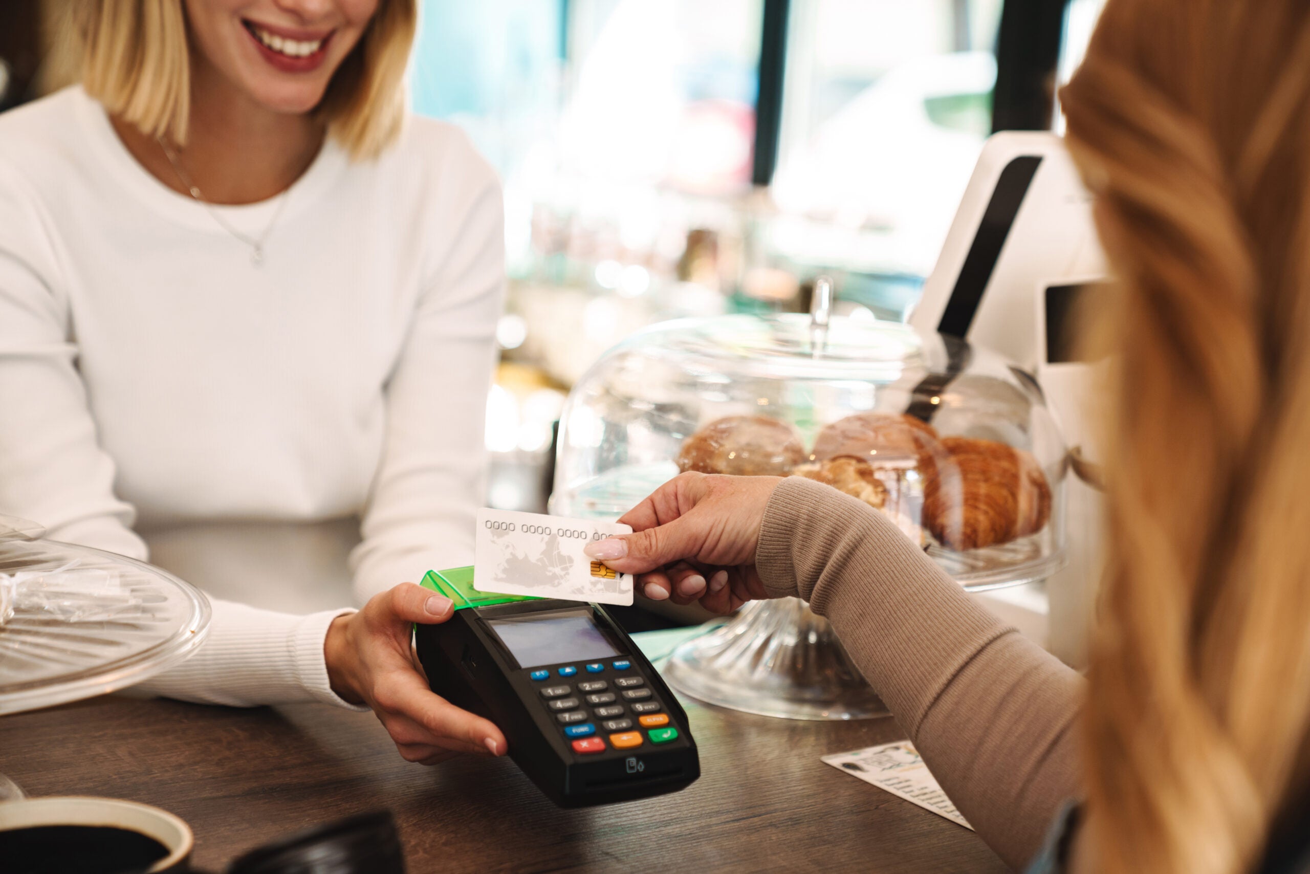 Cropped photo of mature woman paying credit card in cafe Cropped photo of mature woman paying credit card in cafe while waiter holding payment terminal