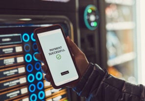 Consumer paying for product at vending machine using contactless method of payment with mobile phone. Woman using payment app on smartphone to buy product. Female hand holding smart phone with payment confirmation on screen
