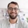 Headshot of cheerful mature european man with beard in glasses look at laptop webcam at minimalist living room