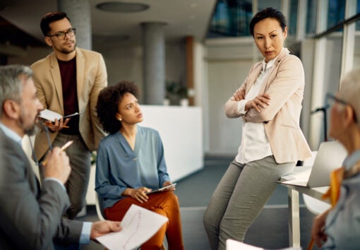 Confident CEO communicating with her business team during a briefing in the office.