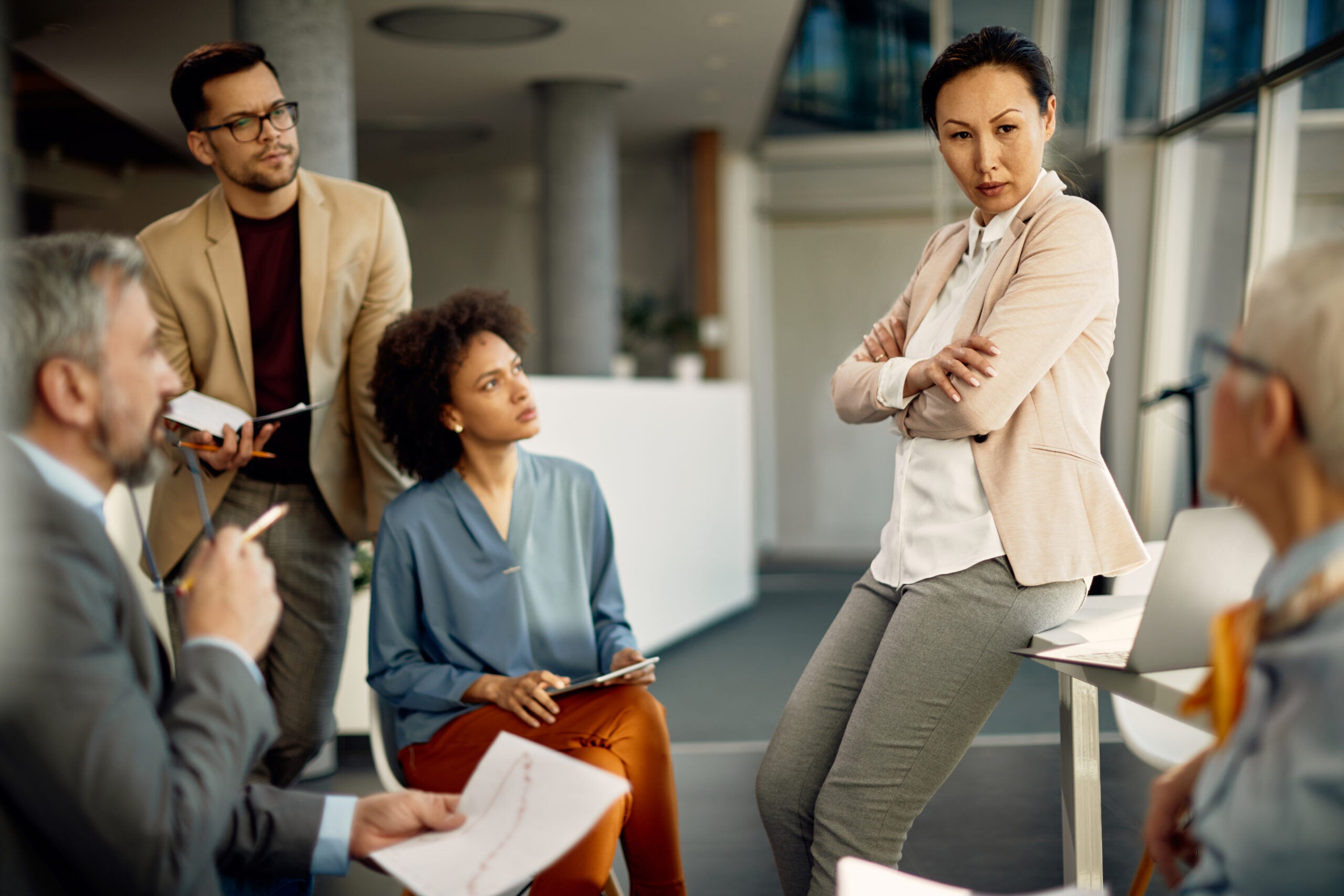 Confident CEO communicating with her business team during a briefing in the office.