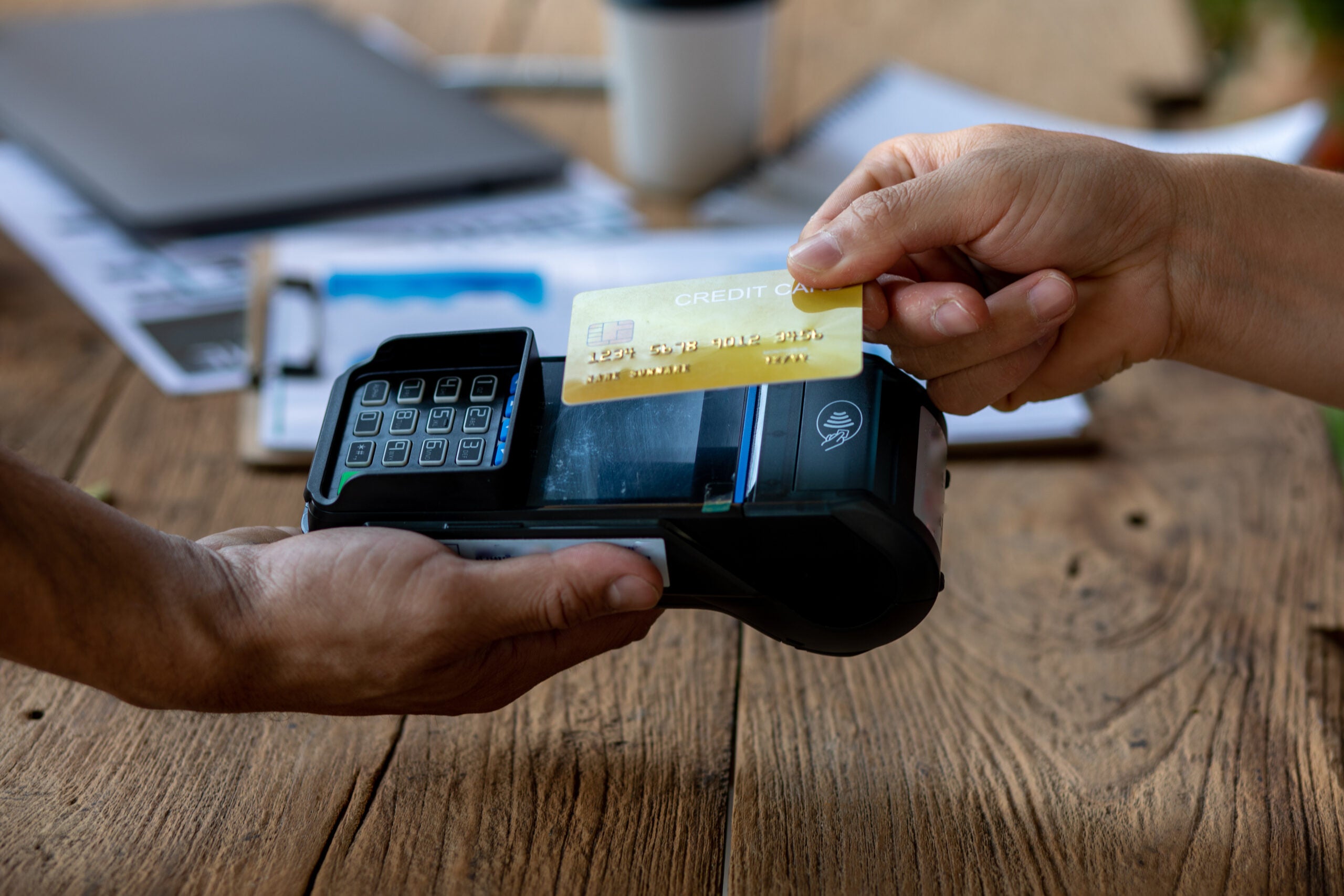 Hands of cafe visitor holding credit card and putting it to the card payment machine,modern bank payment terminal to process acquire credit card payments,