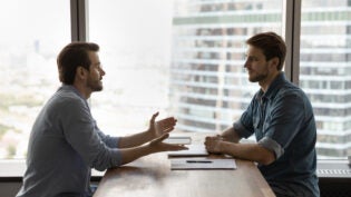 Confident young male job seeker talking with skilled hr manager.