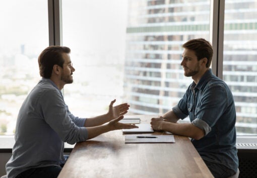 Confident young male job seeker talking with skilled hr manager.