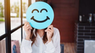 woman holding blue happy smile face on paper cut,