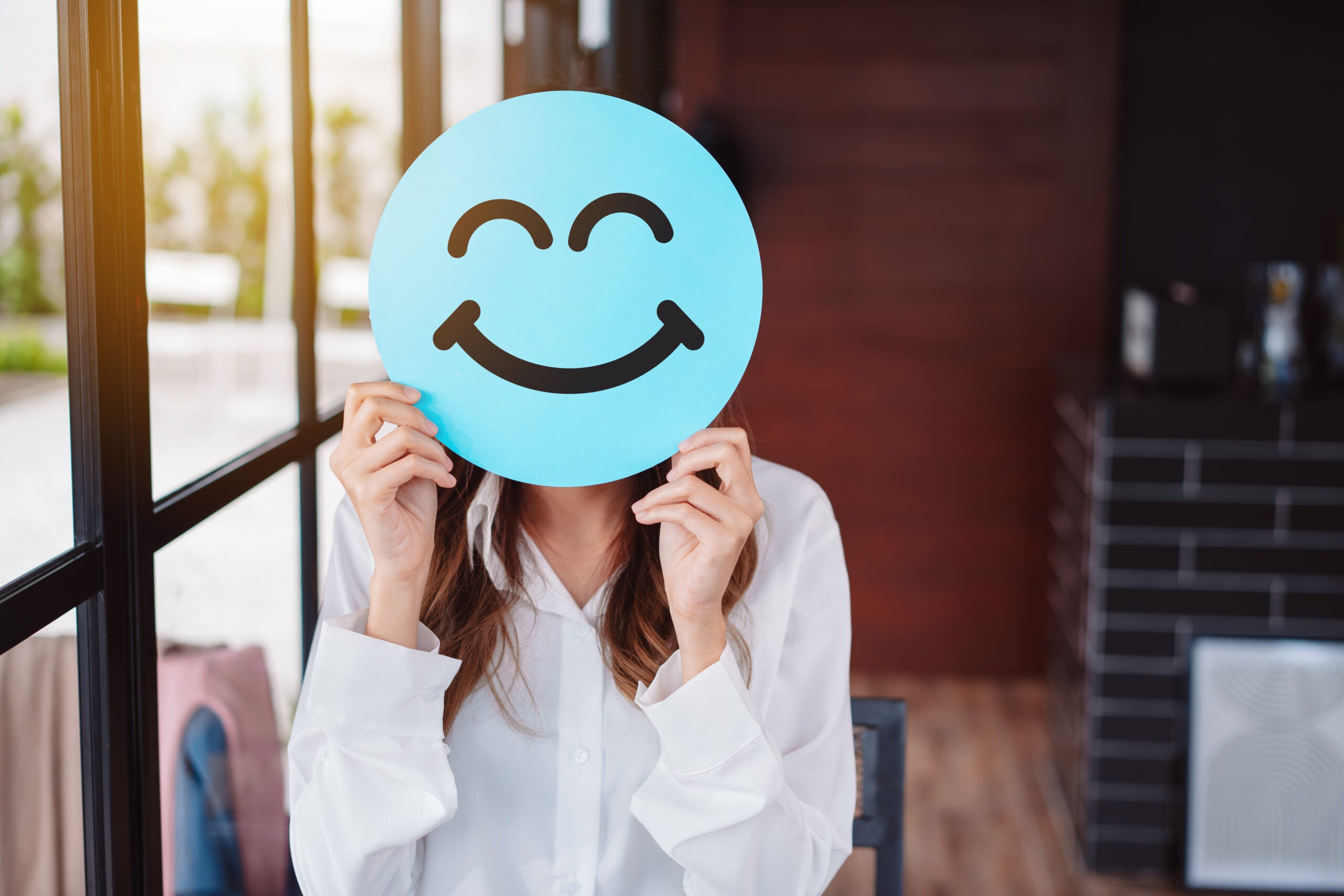Asian woman holding blue happy smile face on paper cut, user giv woman holding blue happy smile face on paper cut,