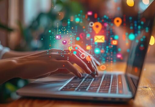 Hand is shown operating a sleek, modern laptop, scrolling through an array of social networks, embodying the concept of home-based social media management. This advanced tech community