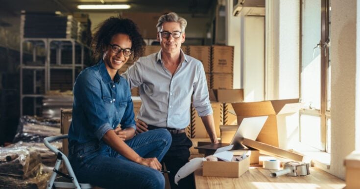 man and woman smiling next to cardboard boxes
