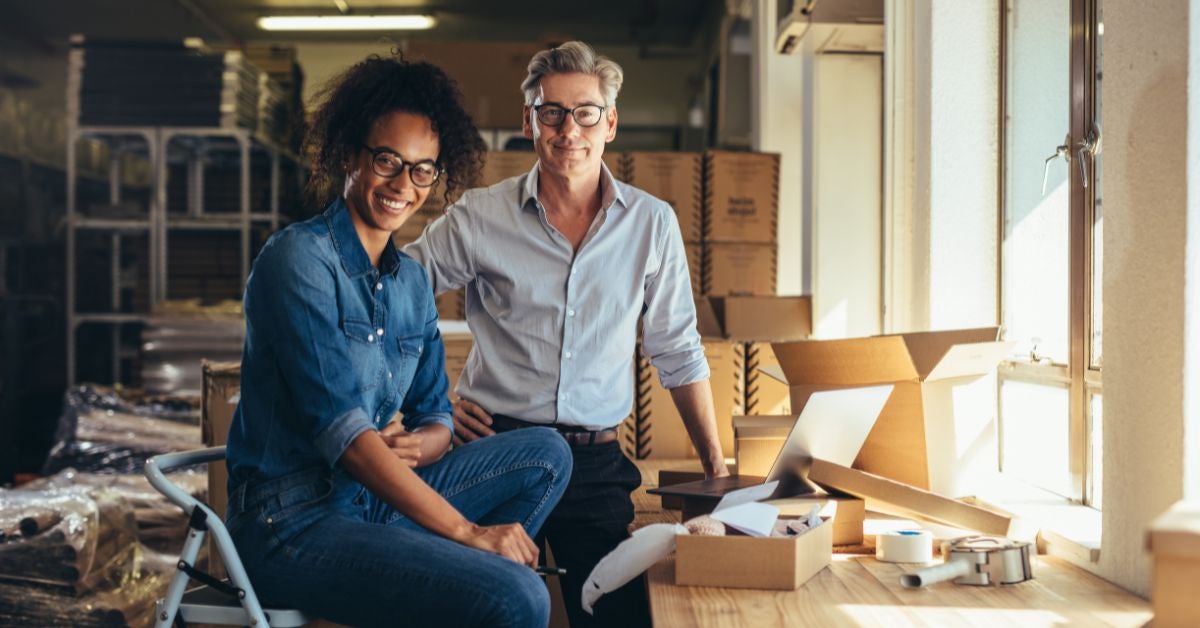 onlinesittingstanding-image1 man and woman smiling next to cardboard boxes