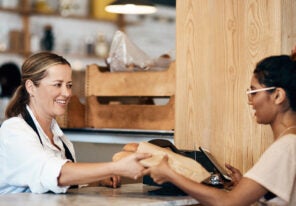 People, customer and phone for bakery payment, digital wallet and tap for breakfast transaction. Women, cashier and helping person with sale in restaurant, takeaway and internet for buying food