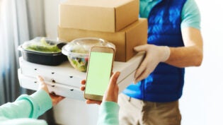 POV of woman using smarthone for ordering online, receiving takeout food from delivery man.